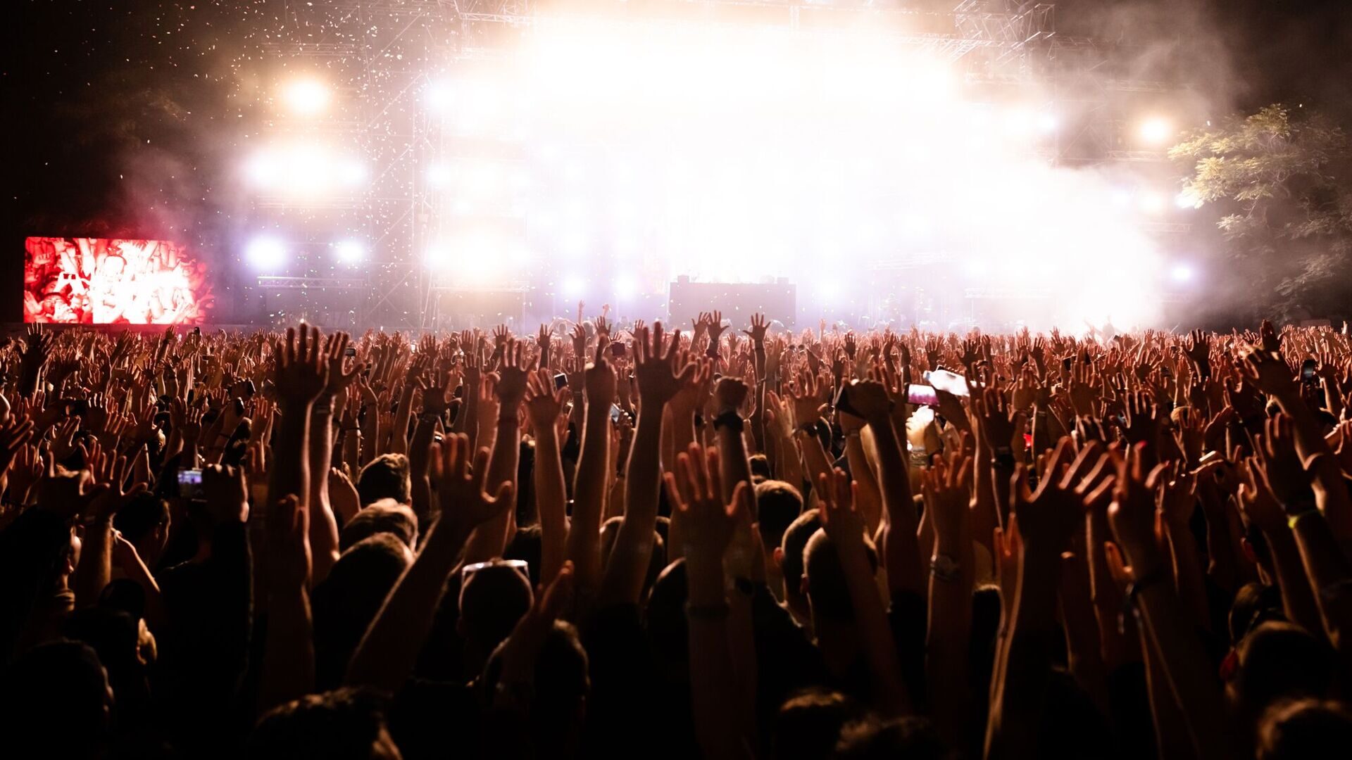 rear-view-excited-people-with-arms-raised-having-fun-while-watching-confetti-fireworks-front-stage-music-festival-copy-space